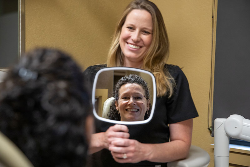 patient smiling in the mirror after their dental procedure