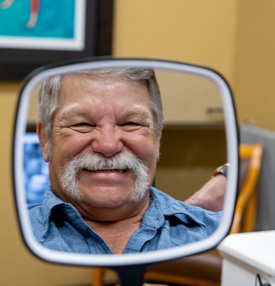patient smiling in the mirror after their dental procedure